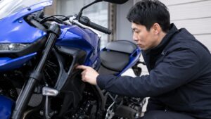 青いバイクのサイドパネル付近でカラーコードを確認する日本人男性
